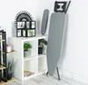 An ironing board and an accessory are shown standing next to a white shelving unit with decorative items and plants. Produktbild-Vorschau