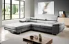 A modern living room with a large sectional sofa, a coffee table, and a large window with curtains.