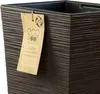 A close-up of a dark brown textured planter with a tag attached. Produktbild-Vorschau