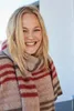 A woman wearing a striped scarf and sweater, smiling. Produktbild-Vorschau