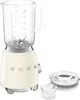 A cream-colored SMEG stand mixer with a glass pitcher and blades is shown on a white background. A separate glass lid and a small glass measuring cup are placed to the right of the mixer. Produktbild-Vorschau