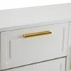 A close-up view of a white cabinet with a gold handle on one of its drawers. Produktbild-Vorschau