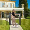 A woman is opening a garden gate in front of a house. Produktbild-Vorschau