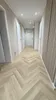 A hallway with herringbone flooring and several doors. Produktbild-Vorschau