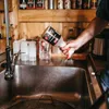 A person is spraying a cleaning product into a sink. Produktbild-Vorschau