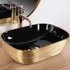 A black and gold vessel sink with a gold faucet and a reflection in a mirror. Anteprima dell’immagine prodotto