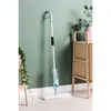 A spray mop is leaning against a green wall next to a wooden cabinet and a plant. Náhled obrázku produktu