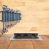 A retractable power outlet is installed in a wooden surface, with a set of wrenches mounted on the wall above it. Produktbild-Vorschau