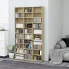 A tall, light brown wooden bookshelf filled with books and other items, placed in a room with a gray carpet and a sofa in the background. Anteprima dell’immagine prodotto