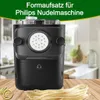A black pasta maker attachment is shown on a wooden table, with a blurred kitchen background. A pile of uncooked spaghetti is in the foreground. Produktbild-Vorschau