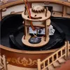 Close-up view of the internal mechanism of a wooden carousel model, showing gears, wires, and a small speaker. Produktbild-Vorschau