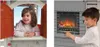 A collage of two images showing children interacting with a playhouse. The left image shows a young girl looking out of a window of the playhouse. The right image shows a young boy interacting with a play fireplace feature. Produktbild-Vorschau