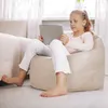 A young girl is sitting on a bean bag chair and using a tablet. Produktbild-Vorschau