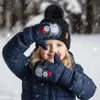 A young girl wearing winter clothing, including a hat and mittens, is posing in the snow. Náhled obrázku produktu