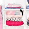 A closet shelf with vacuum-sealed clothes on the top shelf and stacked folded clothes on the middle shelf. An arrow indicates compression. Voir les images du produit