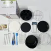 A collection of air fryer accessories laid out on a white surface, including a box, baking molds, racks, tongs, and a brush. Voir les images du produit