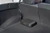 The image shows the interior of a car trunk with a compact subwoofer placed on the floor. Produktbild-Vorschau