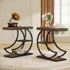 Two industrial-style side tables with a crescent moon-shaped metal frame and wooden shelves are placed in a living room setting. One table has a vintage gramophone and magazines on top, while the other has a vase of flowers and books. The tables are on a p Produktbild-Vorschau