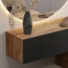 A close-up view of a modern hallway cabinet with a wooden top and a dark gray front, featuring a decorative vase and dried plants, with a backlit mirror in the background. Produktbild-Vorschau