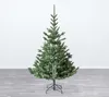 An artificial Christmas tree with a stand, set up indoors against a white wall and on a wooden floor. Produktbild-Vorschau
