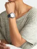 A person wearing a grey t-shirt and a blue watch. Voir les images du produit