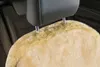 Close-up of a beige sheepskin car seat cover attached to a car headrest. Produktbild-Vorschau