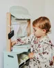 A young child playing with a wooden market stall. Produktbild-Vorschau