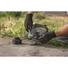 A person wearing black gloves is assembling a Bosch Akku-Freischneider on a paved surface with grass in the background. Voir les images du produit