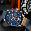 A close-up shot of a men's wristwatch with a blue dial and gold accents, placed on a dark textured surface, with a bottle of Jack Daniel's whiskey blurred in the background. Produktbild-Vorschau