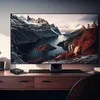 A modern TV setup with a large screen displaying a scenic landscape, placed on a wooden desk with a media player in front. Anteprima dell’immagine prodotto