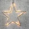 A black wire star outline with warm white LED lights is hanging against a textured gray wall. Produktbild-Vorschau