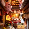 A miniature diorama of a Japanese alleyway with a ramen shop, cherry blossoms, and lanterns. Voir les images du produit