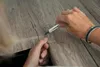 A close-up shot of hands using a utility knife to cut a wood-patterned adhesive film. Podgląd zdjęcia produktu