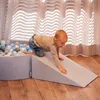 A baby is playing on a foam playground with a ball pit and a ramp. Produktbild-Vorschau