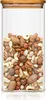 A clear glass jar filled with a variety of nuts, topped with a bamboo lid. Produktbild-Vorschau