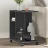 A dark gray side table with wheels is placed next to a light-colored sofa. The table has shelves and is decorated with vases and a lantern. Podgląd zdjęcia produktu