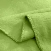 A close-up view of a folded green fleece blanket, showing the texture and stitching of the hem. Produktbild-Vorschau