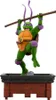 A figurine of Donatello from Teenage Mutant Ninja Turtles, posed dynamically on a brick platform. Podgląd zdjęcia produktu