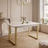 A white dining table with gold legs is shown in a room with decorative wall molding and a large window with curtains. Náhľad obrázku produktu