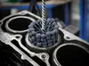A close-up of a cylinder hone tool being used inside a cylinder of an engine block. Voir les images du produit