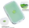 A top-down view of a green silicone food container with its lid slightly ajar, showing a close-up of its features. Produktbild-Vorschau