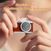 Hands holding a small, vintage-style digital camera. Produktbild-Vorschau