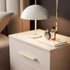 A close-up of a bedside table with a lamp, perfume bottles, and a book. Produktbild-Vorschau
