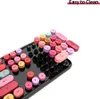 A collection of colorful, retro-style keyboard keycaps scattered on a black keyboard. Náhled obrázku produktu