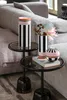 Two vases and a decorative sphere are placed on small side tables next to a sofa. Voir les images du produit