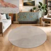 A circular rug is placed on a wooden floor in a living room setting, with a sofa, cabinet, and armchair visible. Voir les images du produit