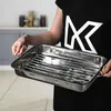 A person is holding a roasting pan with a rack inside. Voir les images du produit