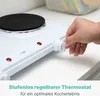 A hand is shown adjusting the thermostat knob on a white electric hot plate. Náhled obrázku produktu