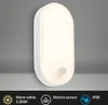 A white oval LED wall light with a motion sensor, mounted on a gray wall. Produktbild-Vorschau