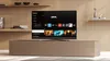 A modern living room with a TV on a stand, displaying a smart TV interface. Produktbild-Vorschau